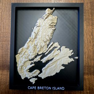 A printed Cape Breton Island seated in its black frame, one solid object.